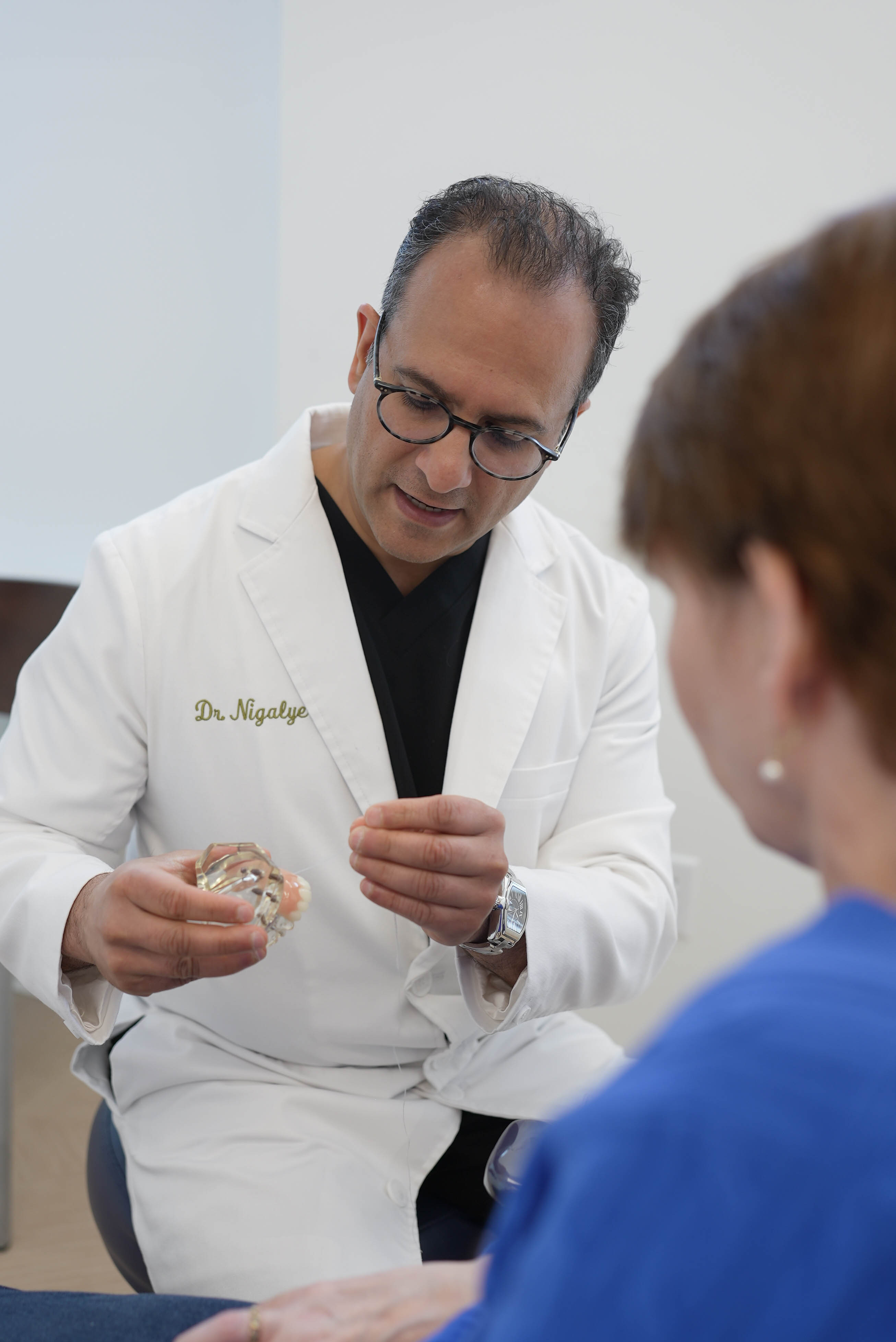 Dr. Nigalye consulting with a patient using a dental model