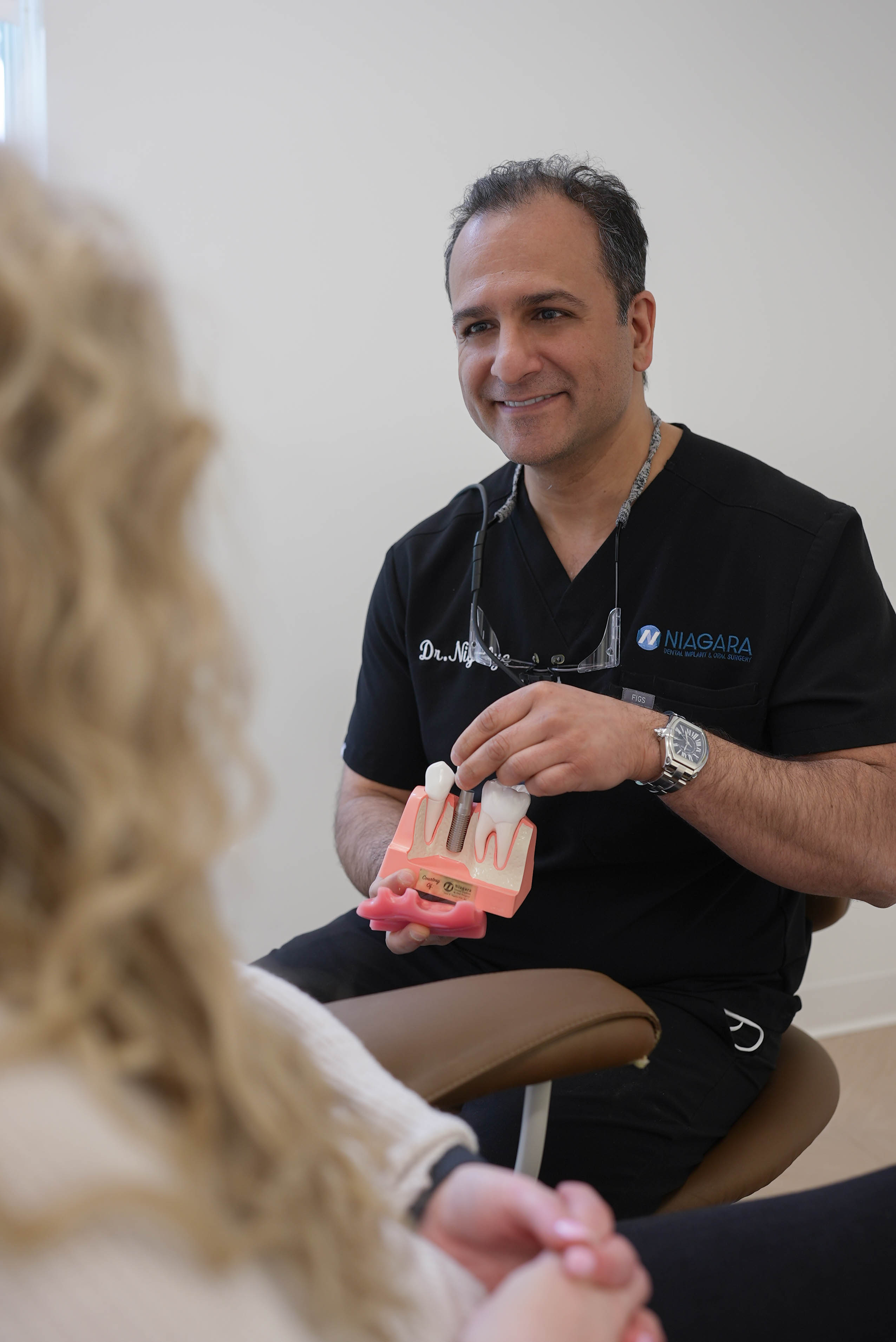 Dr. Nigalye explaining a dental implant model to a patient